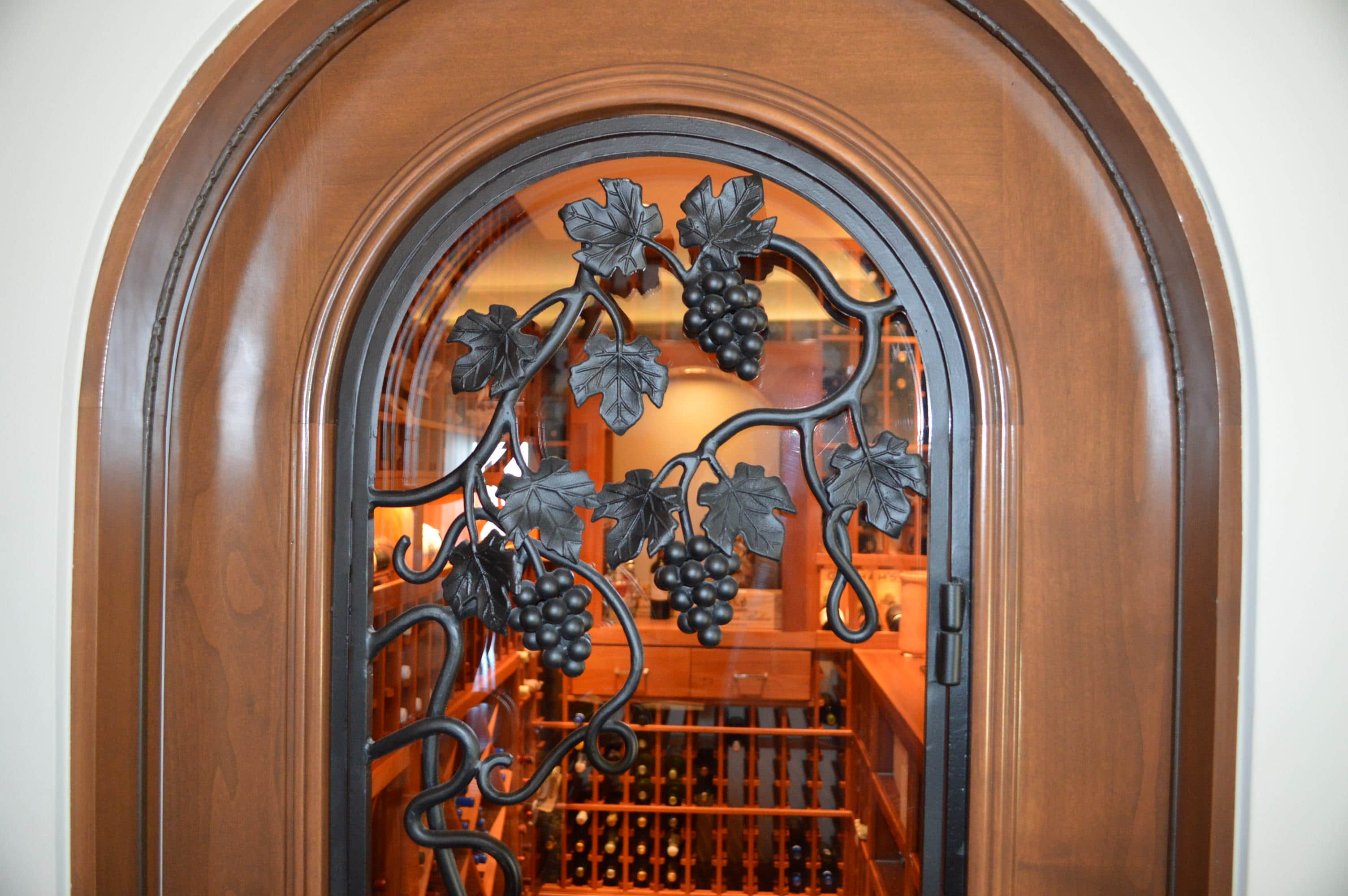 Arched wooden wine cellar door, with intricate design details. Click for a larger image!